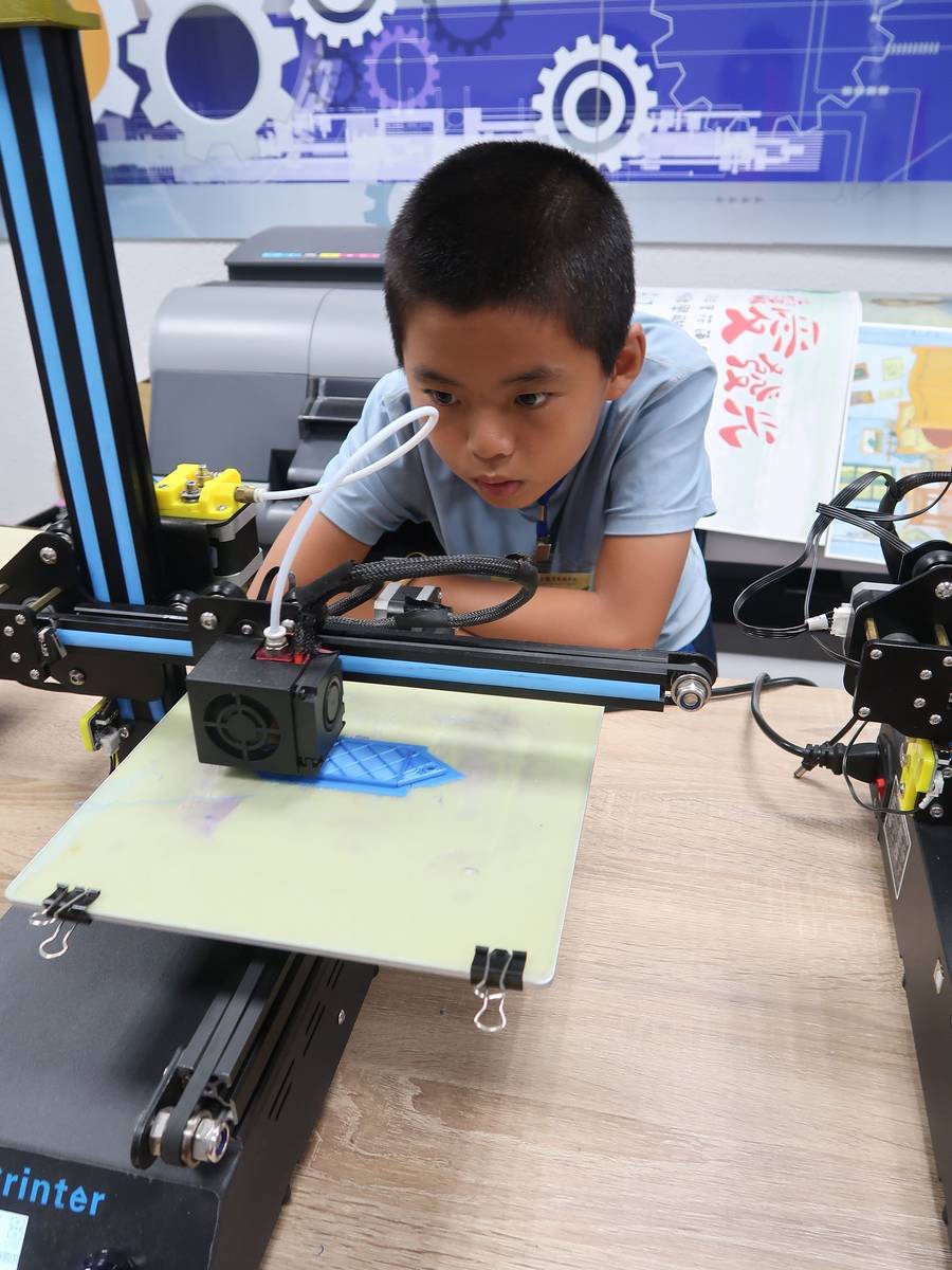 一位同學目不轉睛盯著自己透過3D列印機逐漸成形的作品