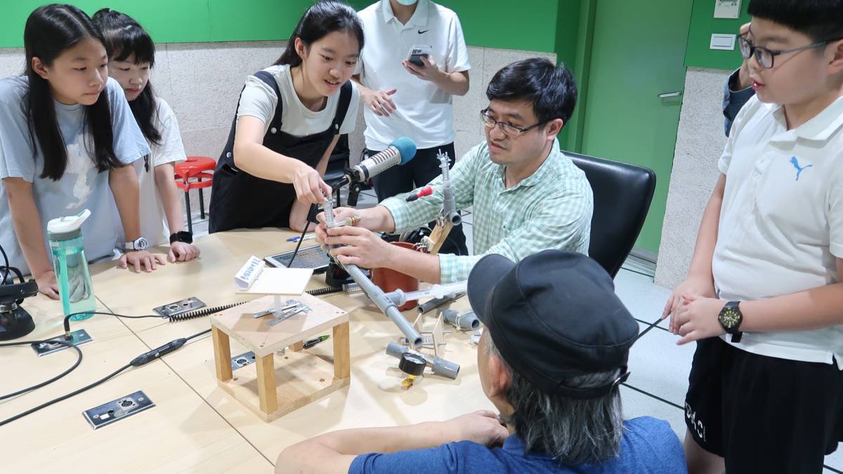 臺中市私立明道普霖斯頓小學科展團隊帶著他們的澆水神器-等壓出水裝置造訪錄音室，主持人看得津津有味。