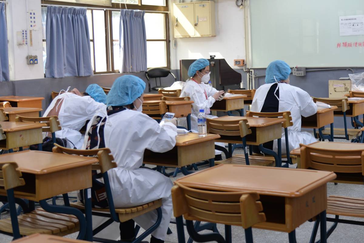 學測首次開放確診輕症、無症狀及快篩陽性考生應考。防疫考場中試務人員均著防護衣。