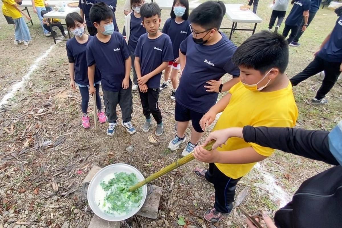 將白米和野菜放入鍋中不斷翻攪，溫泉國小學童體驗製作排灣族傳統美食「搖搖飯」。