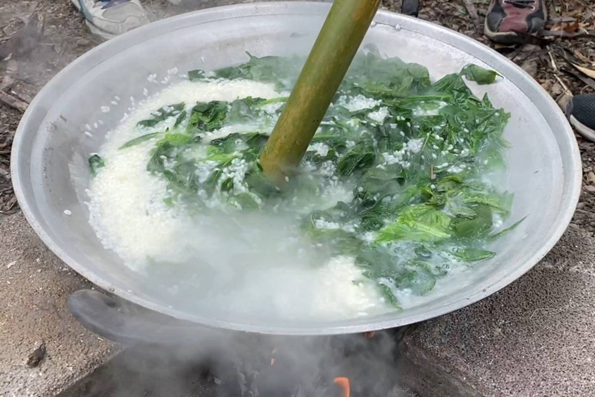 將白米和野菜放入鍋中不斷翻攪，溫泉國小學童體驗製作排灣族傳統美食「搖搖飯」。