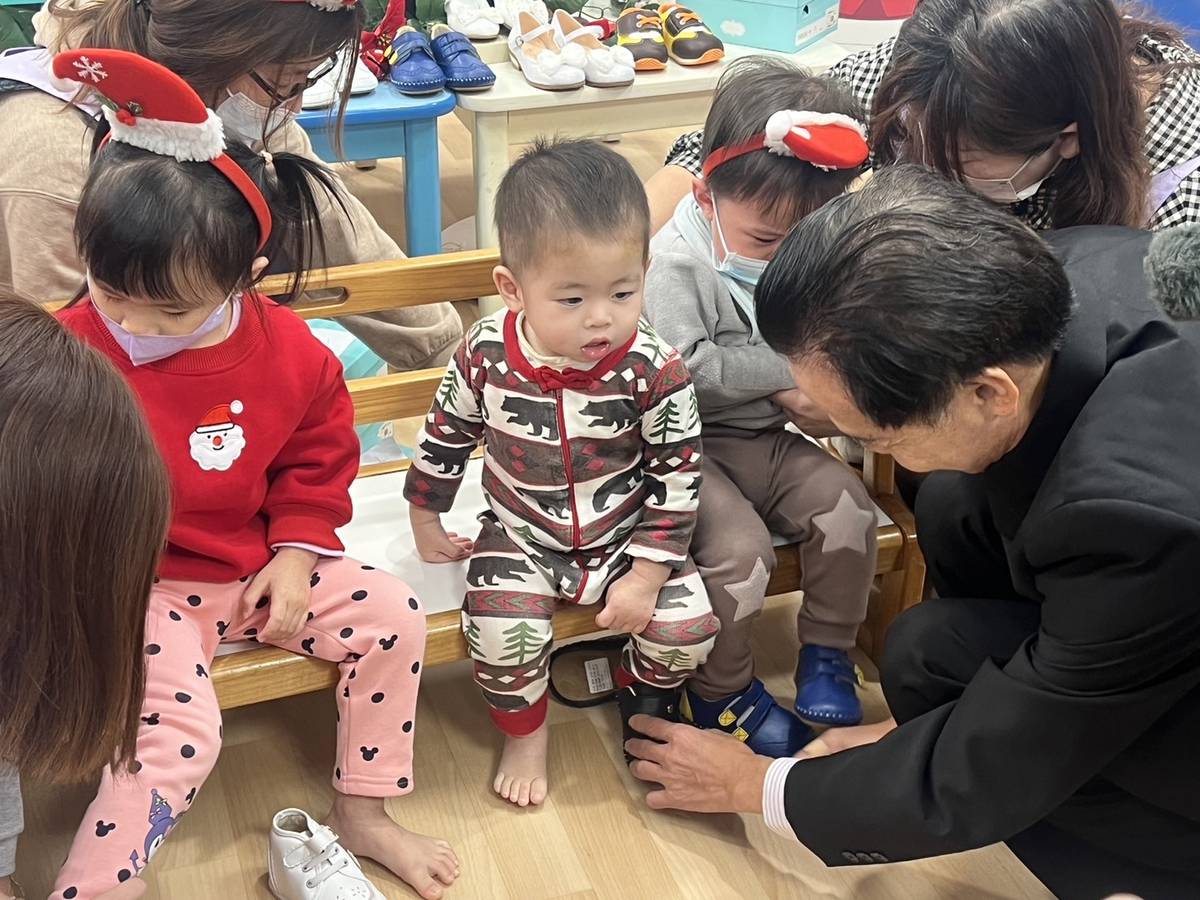 美萬新企業總經理王秋鴻為孩童穿上鞋子