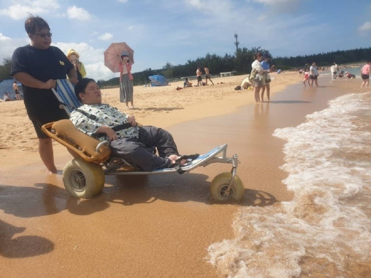黃柏威同學乘坐沙灘輪椅，在資源教室輔導人員協助下，首次體驗海邊戲水  (教育部提供)