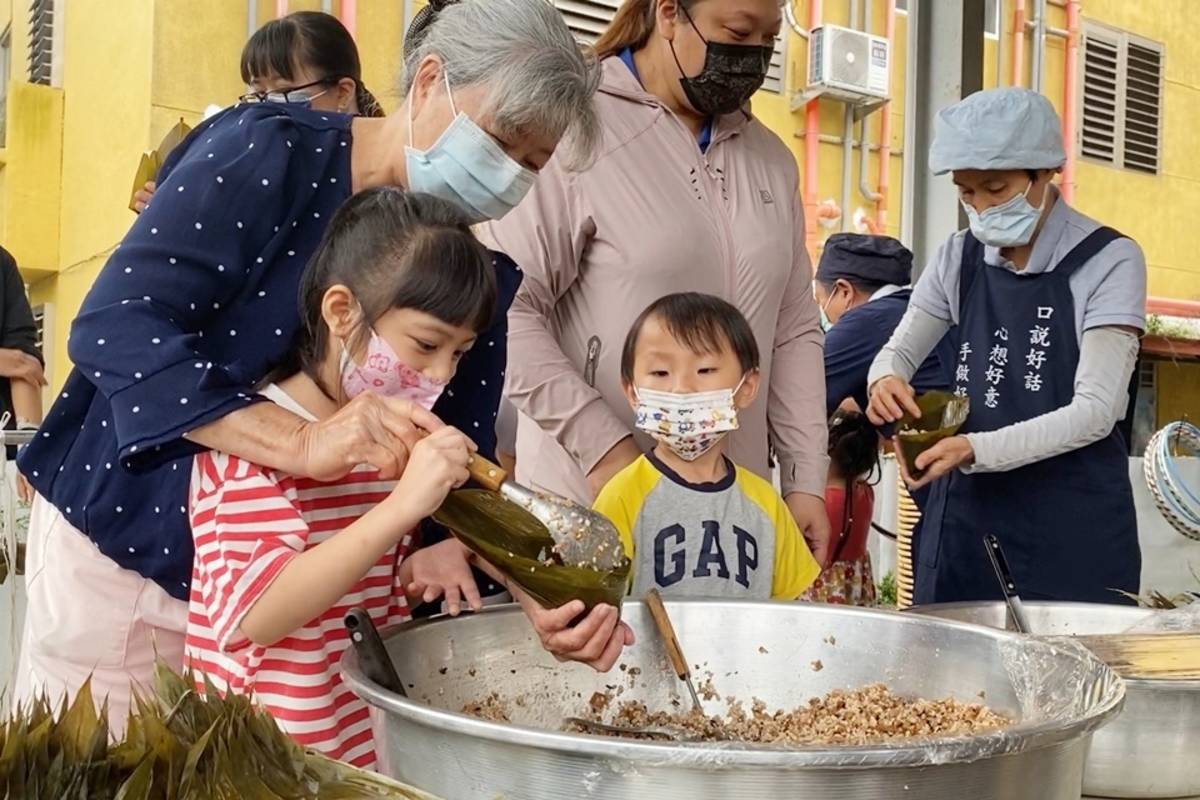 在老師、醫護及社區民眾指導下，幼兒園學童嘗試親手包粽子，將分別送給警消人員、療養院及捐血民眾。