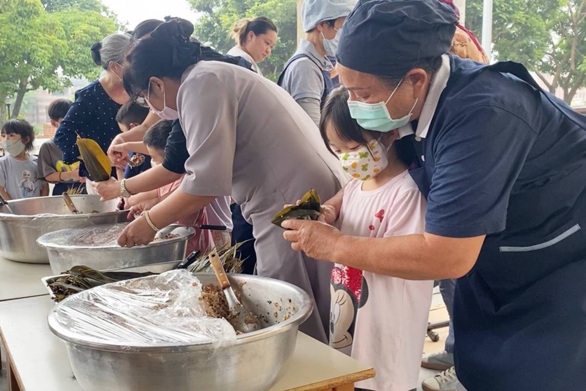 在老師、醫護及社區民眾指導下，幼兒園學童嘗試親手包粽子，將分別送給警消人員、療養院及捐血民眾。