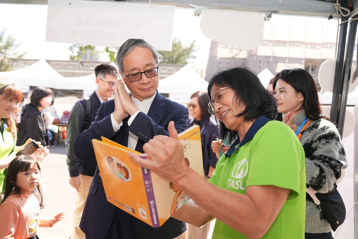 「國家語言生活節」創新書市匯聚多元母語書籍，文化部長李遠（左）於現場從書本學習手語 (文化部提供)