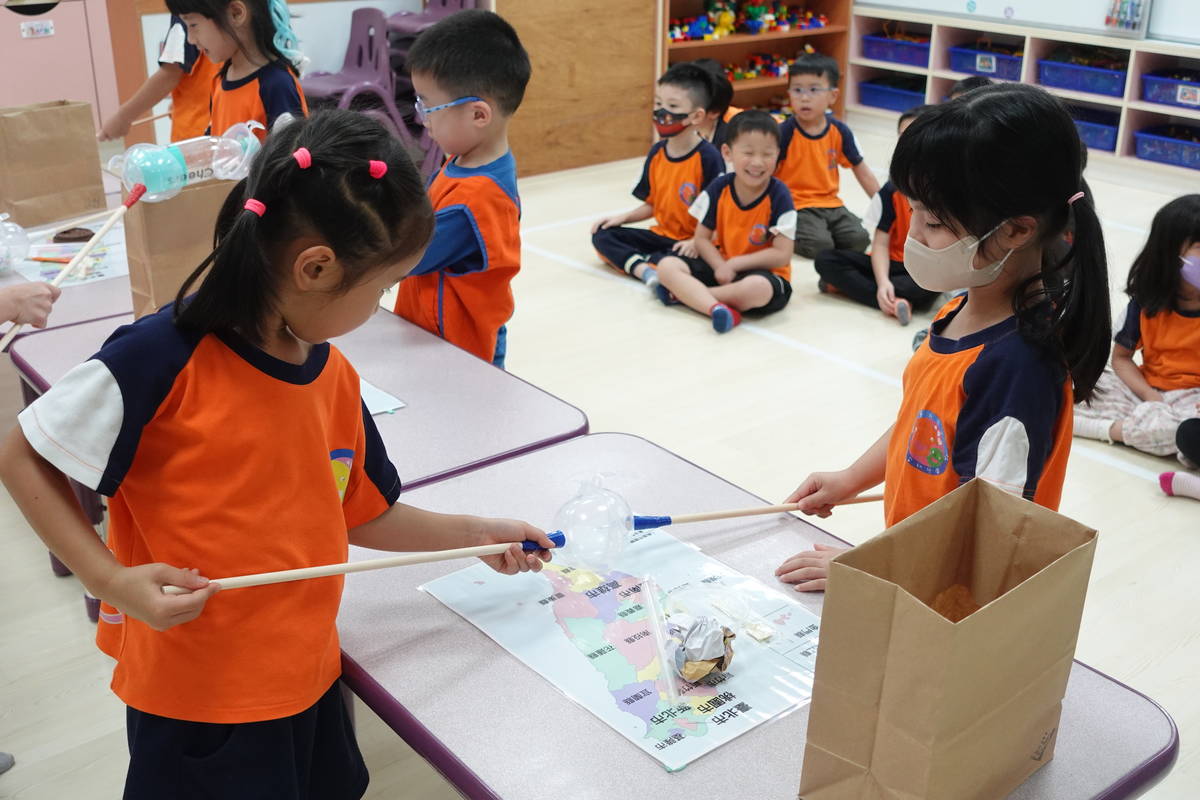 幼兒協力將散落在地圖上不同類型的垃圾集中清理，學習垃圾不落地的環境守護精神
