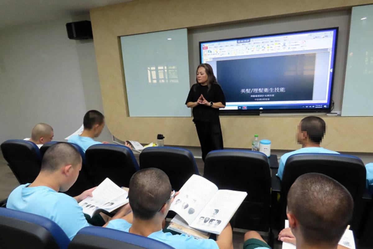 美髮系助理教授陳佳惠（立者）為勵志中學男子理髮丙級考照輔導班學生上理髮衛生課程。