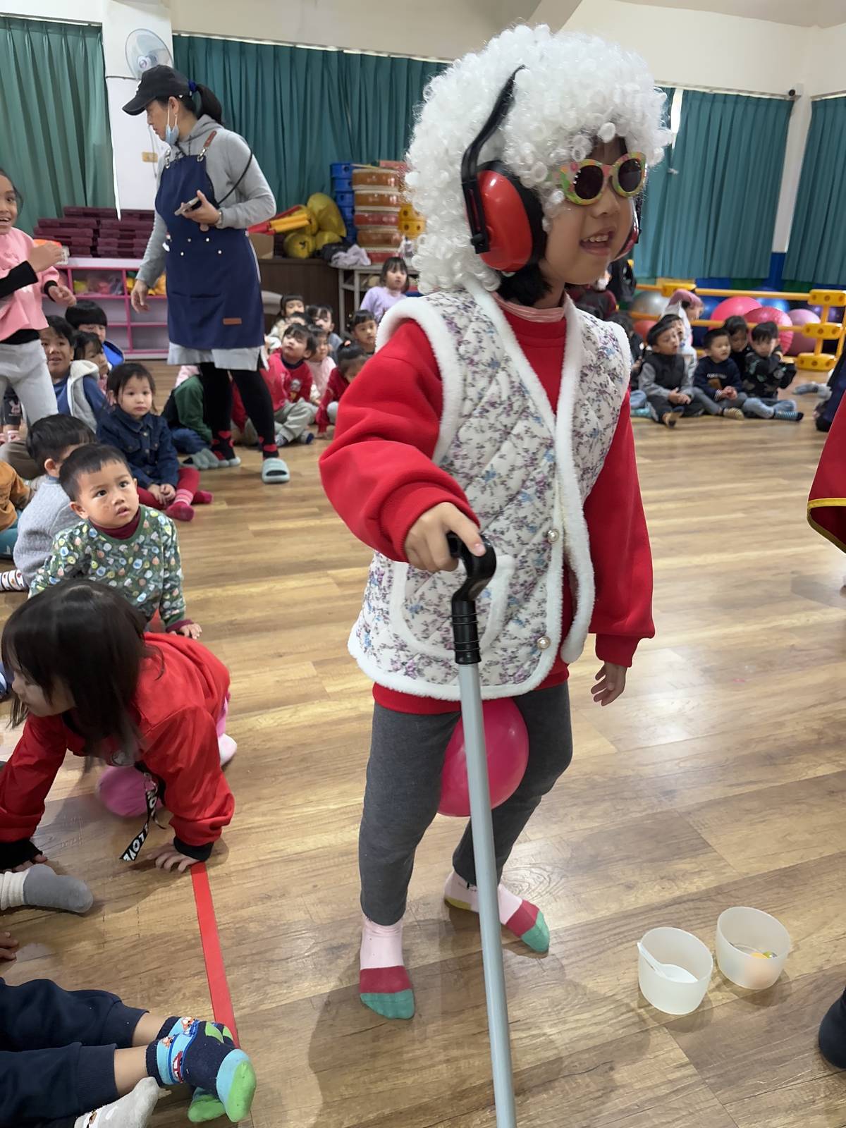 小朋友戴上白色假髮、耳罩，拿拐杖體驗長者的不便